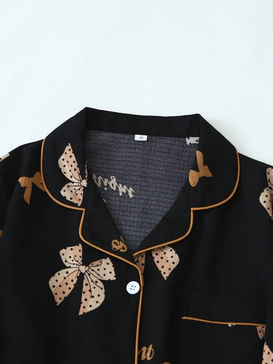 SHEIN طقم بيجامة قطعتين من الستان بقميص بأزرار أمامية وجيوب ونقشة فيونكات وبنطال طويل مجعد بلون أسود